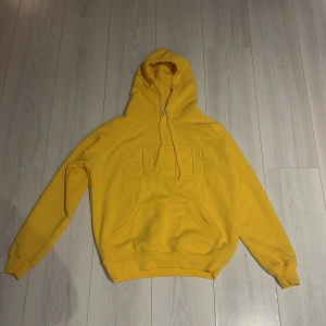 Gul hoodie från Bik Bok - Säljer en cool gul hoodie från Bik Bok med texten 'SLEEP' i relief på framsidan. Den har en klassisk känguruficka och justerbar huva med dragsko. Väldigt bra skick 8/10 som ny typ bara utan prislapp! Perfekt för en avslappnad stil ✅