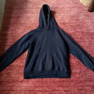 Svart hoodie - Säljer en svart hoodie med en klassisk design. Den har en stor ficka framtill och en bekväm huva. Perfekt för en avslappnad look. Bra använd.