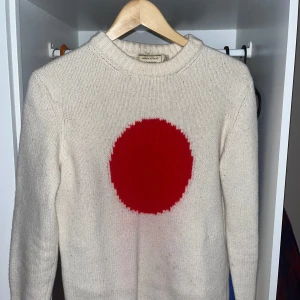 Stickad Maison Kitsune tröja - Säljer en stickad tröja från Maison Kitsune, köptes för några år sen för ca 4000, tröjan är i bra skick utöver att den röda färgen tvättats ur lite. Storlek L men passar mer som M