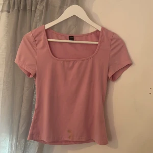 Rosa topp från Shein - Säljer en söt rosa topp från Shein med korta ärmar och fyrkantig halsringning. Har en ganska synbar fläck som går att tvätta bort med diskmedel.