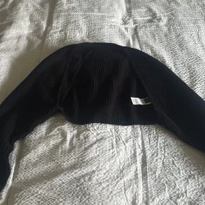 Svart ribbad bolerotopp - Snygg svart ribbad bolerotopp perfekt för lager på lager. Den har långa ärmar och en stilren design som passar till många outfits. Ett måste i garderoben för den som gillar att mixa och matcha.