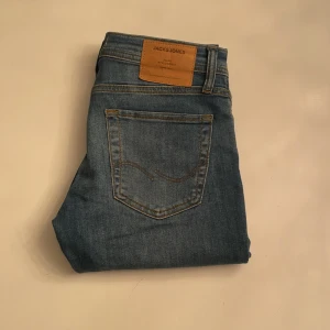 Blå jeans från Jack & Jones - Snygga blå jeans från Jack & Jones med klassisk femficksdesign och en slim fit Glenn passform. Hör av dig vid funderingar!