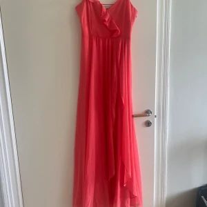 Rosa balklänning med volanger - Korallrosa långklänning med smala axelband och volangdetaljer. Perfekt skick, endast använd en gång.💕🧡