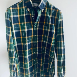 Rutig flanellskjorta från GANT - Rutig flanellskjorta från GANT i grönt, blått och gult. Skjortan har långa ärmar och är i  klassisk design.