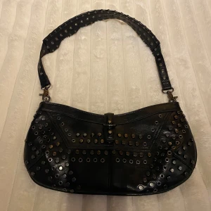 Svart axelväska med nitar💋 - Snygg svart axelväska i skinn med coola nitar över hela ytan. Har använt 1 gång! Så fin men kommer inte till användning💋