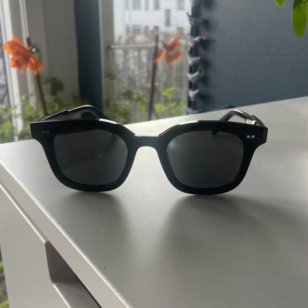 Snygga svarta solglasögon från chimi med klassisk fyrkantig form. De har en stilren design med små silverdetaljer på bågarna. Perfekta för en cool look i solen. Kommer med ett brunt fodral för säker förvaring.. Asusteet.