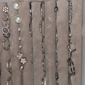 Samling av silverfärgade smycken - En elegant samling av silverfärgade örhängen med olika former och detaljer. Inkluderar stjärnor, månar, pärlor och glittriga stenar. olika pris på smyckena, pris diskuteras😚