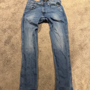 Blå jeans från Replay - Snygga blå jeans från Replay med en klassisk femficksdesign och dragkedja. Perfekt för en avslappnad stil. Märket Replay syns tydligt på insidan av midjan.
