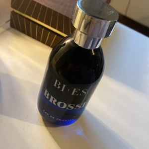 Blå Eau de Toilette från Bi-Es - Säljer en elegant och stilren Eau de Toilette från Bi-Es. Flaskan är i en djupblå färg med en silverfärgad kork som ger en lyxig känsla. Perfekt för både vardag och speciella tillfällen. Flaskan innehåller 100 ml av denna fräscha doft.