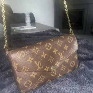 LV väska - LV väska i modellen Felicie Pochette, monogram design i läder. Väskan har en inbyggd inneficka, medföljer en platt avtagbar ficka med 8st korthållare.  Färgen är i fin skick & väskan är sparsamt använd, enda defekten är att knappen kan gå upp ibland.