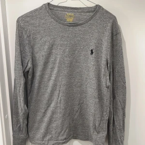 Grå långärmad tröja från Polo Ralph Lauren - Säljer en stilren grå långärmad tröja från Polo Ralph Lauren. Den har en broderad logga på bröstet och är i en slim fit passform. Tröjan är i bomull och superbekväm att ha på sig. Den är i bra skick 8-9/10. Storleken är åt det mindre hållet S-XS.