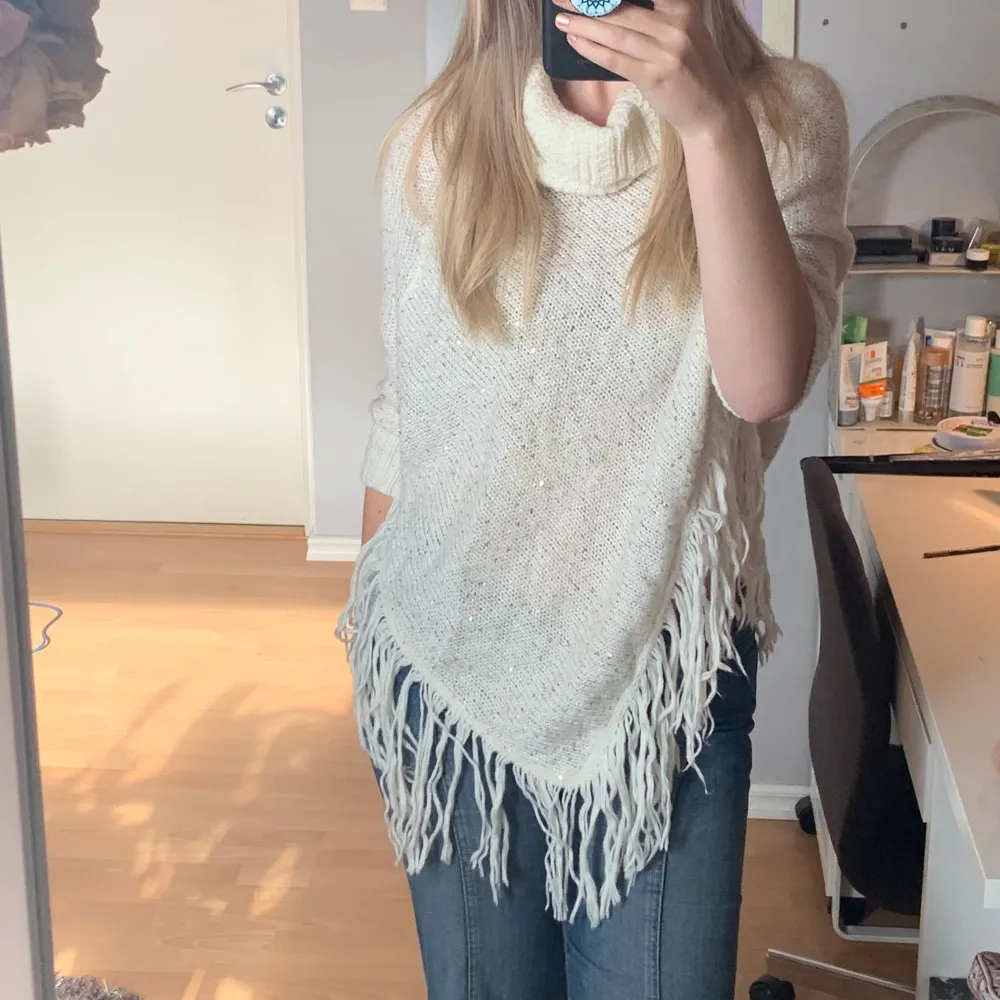 En sååå himla fin vit poncho med glitter. Glittret är guldaktigt och ponchon har små tofsar längst ner som gör den lite extra cutesy. Ponchos är inne igen, hoppa på trenden och ha en unik och snygg en🥰. Stickat.