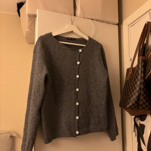 Stickad grå tröja - En stickad gå tröja med knappar som går lite snett ner. Super söt. Storlek s