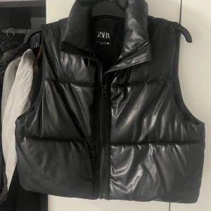 Svart dunväst från Zara - Säljer en snygg svart dunväst från Zara i storlek M. Västen har en dragkedja framtill och är perfekt för höst och vinter. Den är i nyskick och passar bra till både vardag och fest. Superbekväm och stilren!