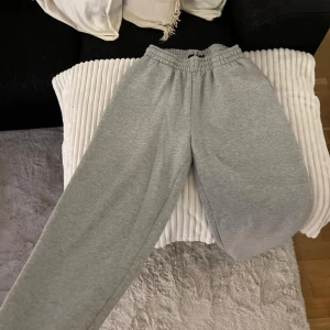 Grå mjukisbyxor - Säljer ett par superbekväma grå mjukisbyxor. Perfekta för att chilla hemma eller köra ett avslappnat träningspass. De har en elastisk midja för extra komfort och är gjorda i ett mjukt material. Passar perfekt för höst- och vintermys!