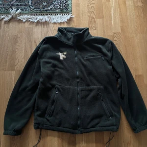 Fleecejacka - Mörkgrön fleece med en guldig älg på bröstet