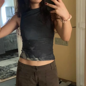 Svart ärmlös topp - Snygg svart ärmlös topp med asymmetrisk design. Perfekt för en trendig look.