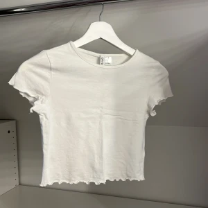 Säljer en vit volang T-shirt från HM  - Vit bomull tröja i storlek XS från HM 