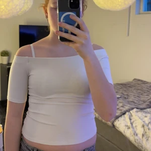 Vit offshoulder topp - Säljer en stilren vit offshoulder topp med korta ärmar. Perfekt för en somrig look. Toppen är tight och framhäver figuren.