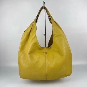 Gul axelväska i skinn - En Stor Hobo-väska från det koreanska märket “Hellenic Jane”. Snygg pastel gul axelväska i äkta skinn med en enkel och stilren design. Väskan har en praktisk axelrem och en diskret logodetalj framtill. Perfekt för att liva upp din outfit med en färgklick. Den riktiga pris är 6,000 kr. Rekommenderas!! 