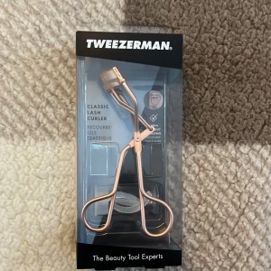 Ögonfransböjare från Tweezerman - Snygg och effektiv ögonfransböjare i roséguld från Tweezerman. Den har en rundad silikonkudde för att ge en skonsam och långvarig böjning av fransarna. 