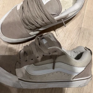 Vans Knu Skool - Säljer ett par snygga beige och vita sneakers från Vans. Skorna har en klassisk design med snörning och en vit sula. Perfekta för en avslappnad stil.