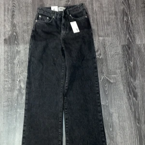 Svarta jeans med raka ben - Snygga svarta jeans med hög midja och raka ben. Klassisk femficksdesign med knapp och dragkedja framtill. Perfekta för en stilren look.