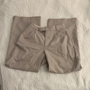 Beige kostymbyxor från H&M - Skitsnygga beige kostymbyxor från H&M med hög midja och rak/baggy passform. I storlek 36. 