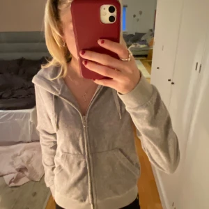 Grå hoodie från Juicy Couture - Säljer en grå hoodie från Juicy Couture med dragkedja och huva. Tröjan har långa ärmar och en praktisk ficka framtill. Köpt för 1200kr men säljer för 900kr💖 hör av er för fler bilder eller frågor!