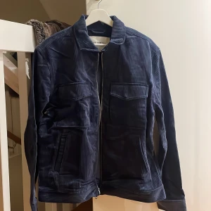 Blå manchesterjacka från These Glory Days - Snygg blå manchesterjacka från These Glory Days med dragkedja framtill. Jackan har långa ärmar och praktiska fickor med lock på bröstet. Perfekt för en stilren look.