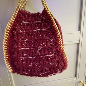 Vinröd stickad axelväska med guldkedja - Snygg vinröd stickad axelväska, säljer pågrund av att jag inte är guld tjej längre.