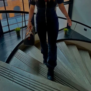 Svart Jumpsuit från Mango, S - Snygg brun skinnväska med handtag i kontrasterande färg. Perfekt för att bära med sig det nödvändigaste med stil. Väskan har en klassisk design som passar till många olika tillfällen.