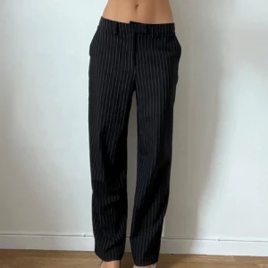 Lågmidjade kostymbyxor - Randiga lågmidjade kostymbyxor en knapp på insidan har lossnat men påverkar inte funktionen se bild 3