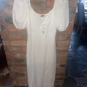 Vit klänning med puffärmar från Gina Tricot - Säljer en stilren vit klänning från Gina Tricot med puffiga kortärmar och en elegant passform. Perfekt för sommarens alla tillfällen. Klänningen har en klassisk design som är lätt att matcha med olika accessoarer. Obs den är en liten s då den e figur sydd. Hör av er om övriga frågor uppstår 