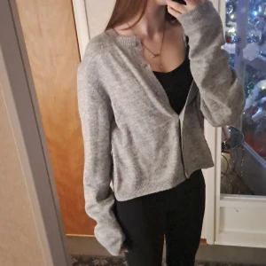 Grå kofta från H&M - Säljer en mysig grå kofta från H&M. Den har långa ärmar och knappar framtill. Perfekt för kyliga dagar och enkel att matcha med olika outfits.