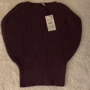 Mörklila stickad tröja från Zara - Säljer en mörklila stickad tröja från Zara. Tröjan har en unik design med breda axlar och en tightare midja, vilket ger en snygg siluett. Perfekt för kyligare dagar. Tyvär satt den inte på mig som jag ville. (Skriv ändats för intresse)💕💕