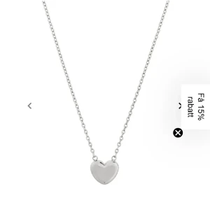 Silverfärgat halsband med hjärta Edblad  - Elegant silverfärgat halsband med ett litet hjärta som hänge. Perfekt för att ge en subtil och romantisk touch till din outfit. Kedjan är tunn och smidig, vilket gör den bekväm att bära hela dagen.