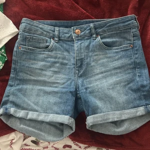 Blå jeansshorts från H&M Divided - Snygga blå jeansshorts från H&M Divided med klassisk femficksdesign och uppvikta ben. Perfekta för en avslappnad stil under varma dagar. 🩳💙