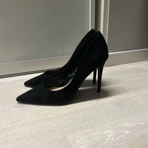 Svarta pumps från Primark - Eleganta svarta pumps från Primark med spetsig tå och hög klack. Perfekta för en stilren look.