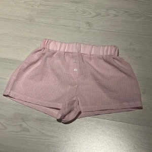 Rosa randiga shorts - Söta rosa shorts med ränder och knappar framtill. De har en elastisk midja. 