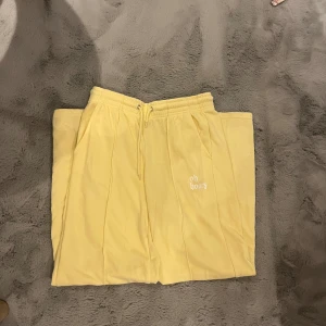 Gula mjukisbyxor med broderi - Snygga gula mjukisbyxor med texten 'oh honey' broderad på ena benet. Byxorna har en bekväm resårmidja med snörning och raka ben. Perfekta för en avslappnad stil.