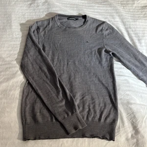 Grå tröja från J.Lindberg -  grå merino-ulltröja från J.Lindberg.           Diskret logga på bröstet.                                Storlek: S inga defekter.                            Produkten levereras tvättad och strykt