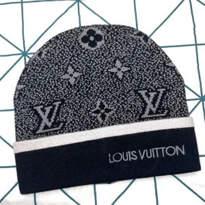 Svart och grå mössa från Louis Vuitton - Stilren svart och grå mössa från Louis Vuitton med ikoniskt mönster och broderad logotyp. Perfekt för att hålla värmen med stil.