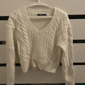 Vit stickad tröja - Mysig vit stickad tröja från F&F med ett snyggt flätmönster och v-ringad hals. Perfekt för kyliga dagar med långa ärmar och ribbade kanter. Storlek M men passar mig perfekt med xs