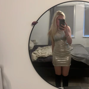 Silverfärgad oneshoulder klänning - Snygg och glittrig silverfärgad oneshoulder klänning som verkligen drar blickarna till sig. Perfekt för en utekväll eller fest. Den har en tight passform som framhäver figuren. 