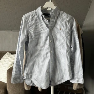 Randig skjorta från Ralph Lauren - Snygg blå- och vitrandig skjorta från Ralph Lauren. Perfekt till våren och sommaren!🌸