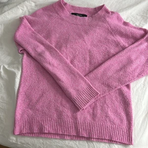 Rosa tröja från Vero Moda - Säljer en mysig rosa tröja från Vero Moda. Tröjan har långa ärmar och ribbade detaljer vid hals, ärmslut och nederkant. Perfekt för kyligare dagar! Är knottrig därav priset ingen fläck eller så.