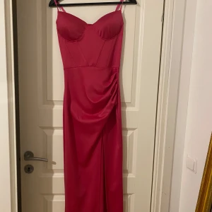 Rosa maxidress - Mörkrosa lång klänning med slit. Köpt utomlands, använt 1 gång, fortfarande i nytt skick. Pris går att diskutera. Passar Xs och S