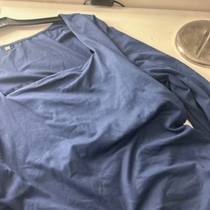 Blå långärmad tröja - Säljer en blå långärmad tröja med v-ringad hals. Perfekt för en avslappnad stil. Tröjan är mjuk och bekväm, idealisk för kyligare dagar.