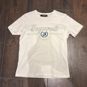 Dsquared2 t-shirt  - Säljer en stilren vit t-shirt från Dsquared2 med blått tryck på framsidan. 